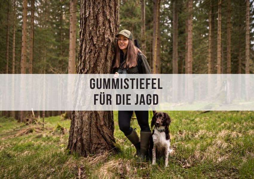 J�gerin mit Gummistiefeln und Hund im Wald
