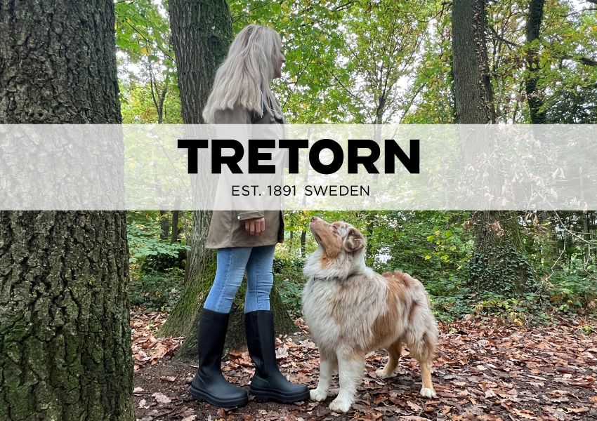 Frau mit Tretorn Gummistiefeln und Jacke im Wald mit Hund