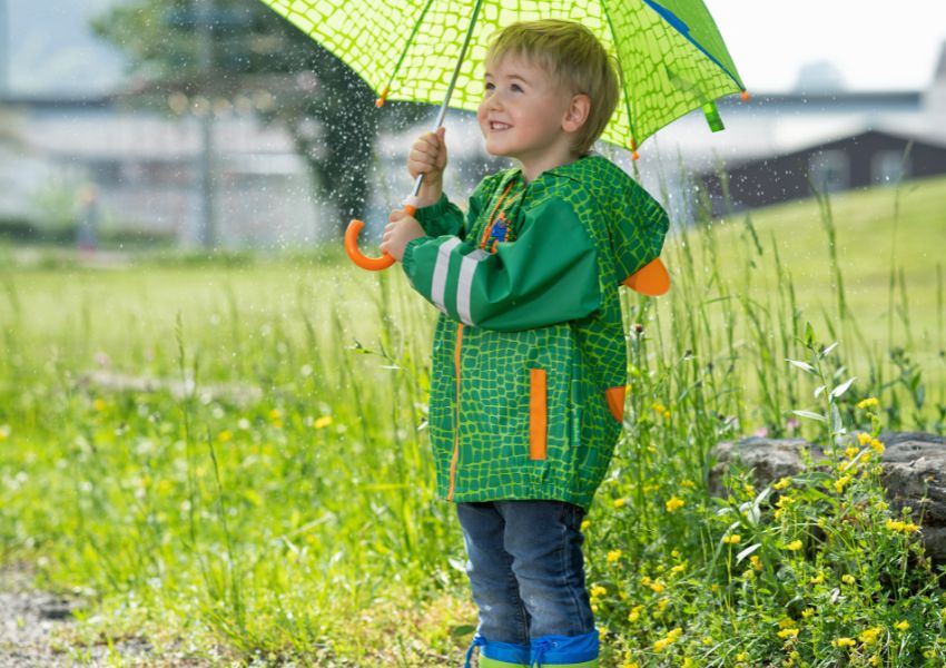 Kinder mit Gummistiefeln und Regenbekleidung